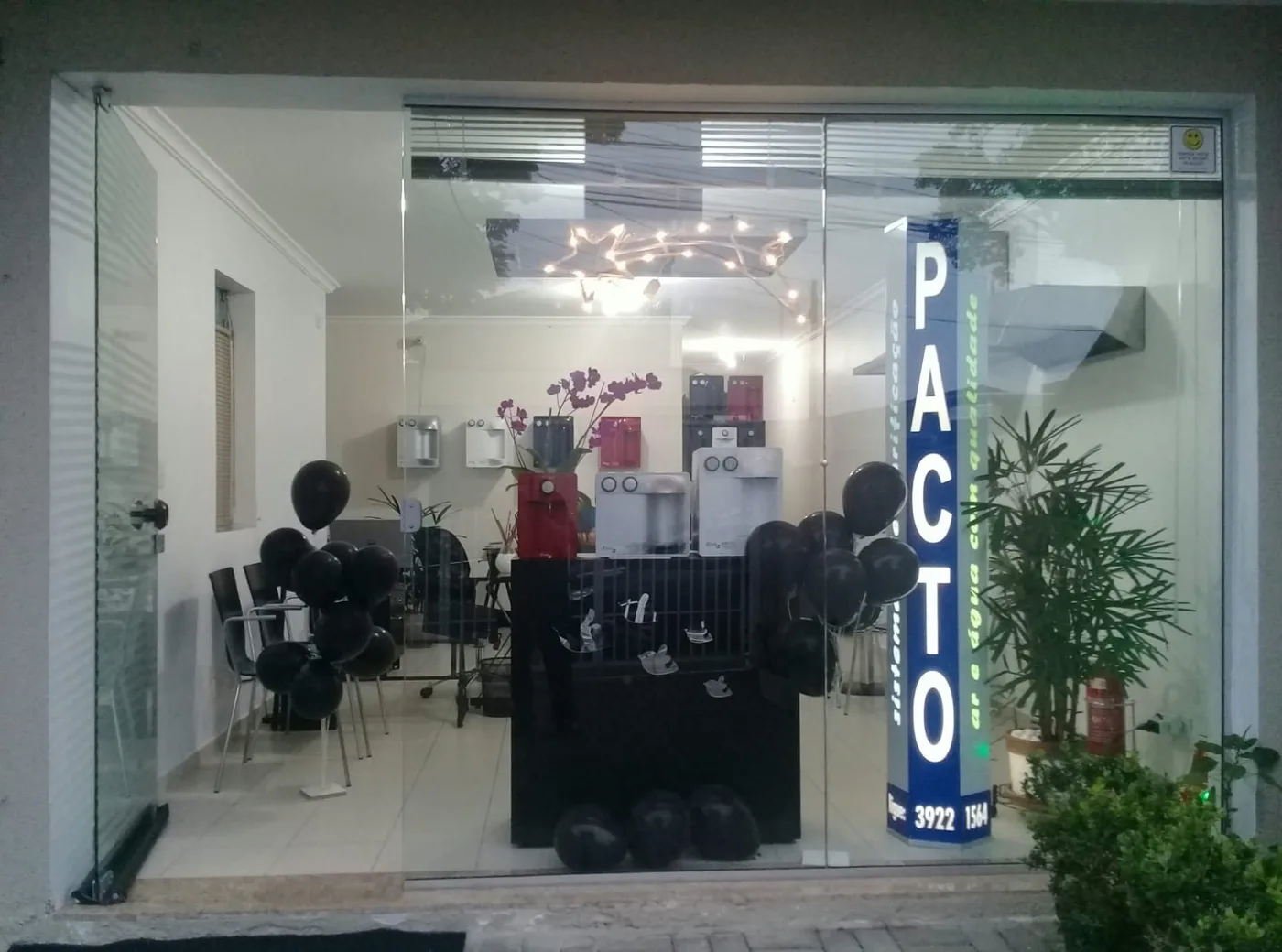 Fachada iluminada do show room da Pacto Purificadores com purificadores em exposição na vitrine