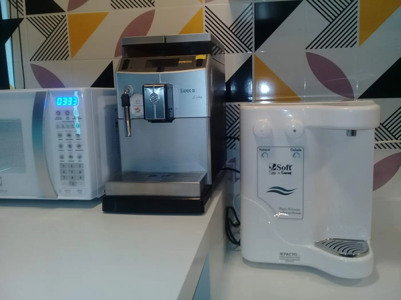 Purificador de água Soft Star branco instalado em bancada de cozinha com azulejo geométrico