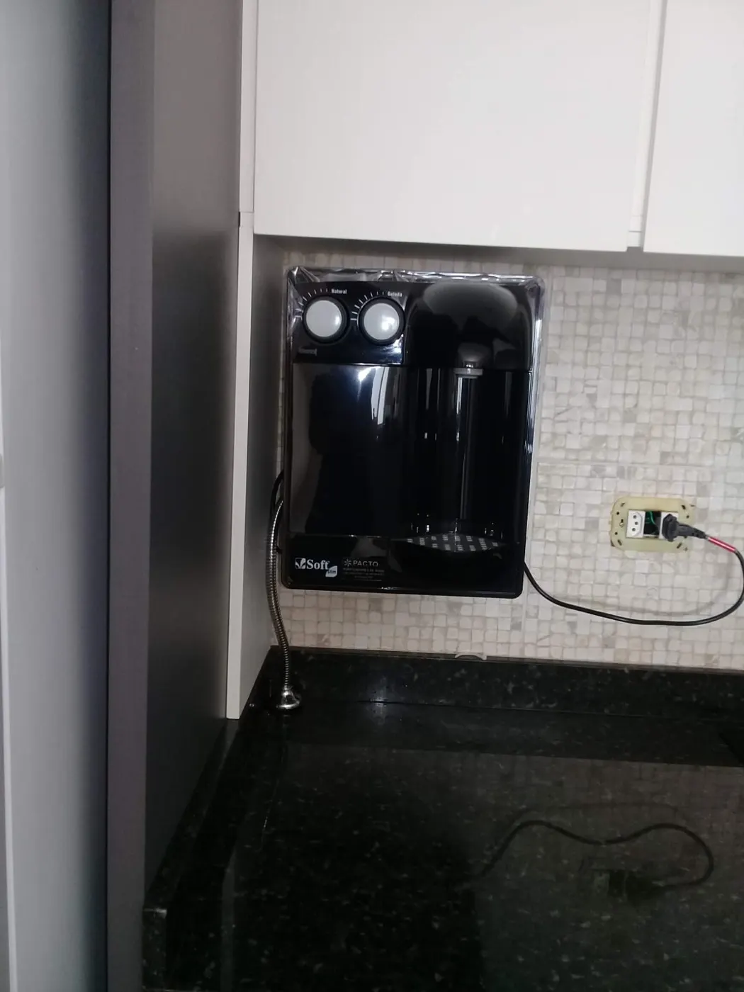 Purificador de água Soft Slim preto instalado em nicho de cozinha com pastilhas claras