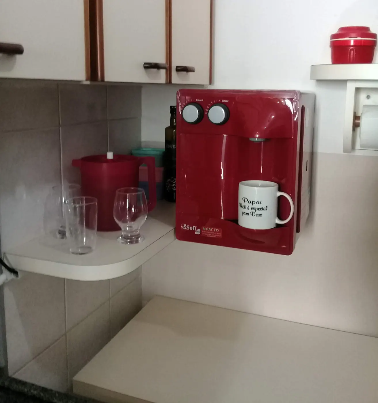 Purificador de água Soft Slim vermelho instalado em parede de cozinha residencial