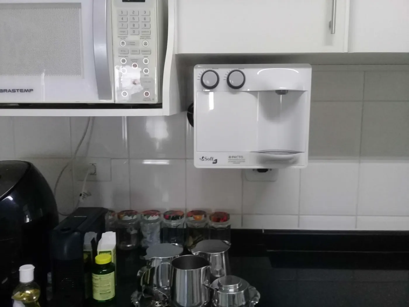 Purificador de água branco instalado na parede ao lado do micro-ondas