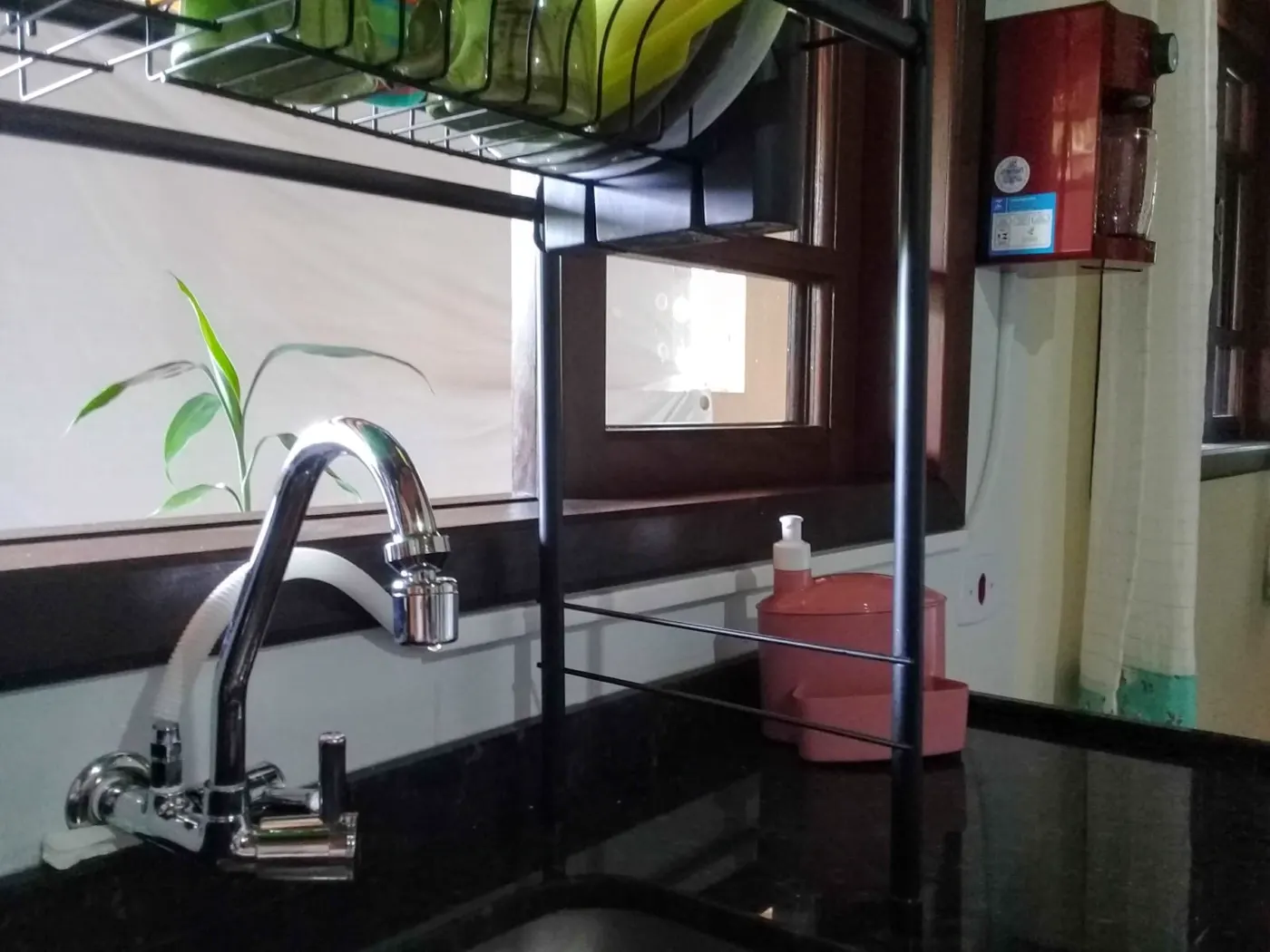 Purificador de água vermelho instalado na parede de uma cozinha residencial