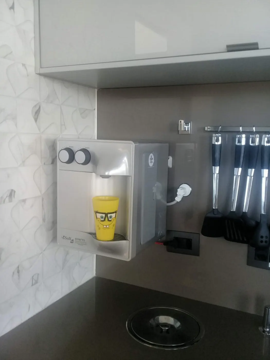 Purificador de água Soft branco instalado em parede de mármore em cozinha planejada